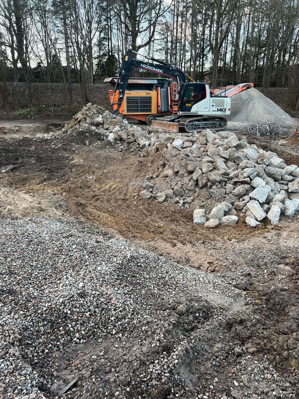 Gravemaskine og knust beton på nedbrydningsplads